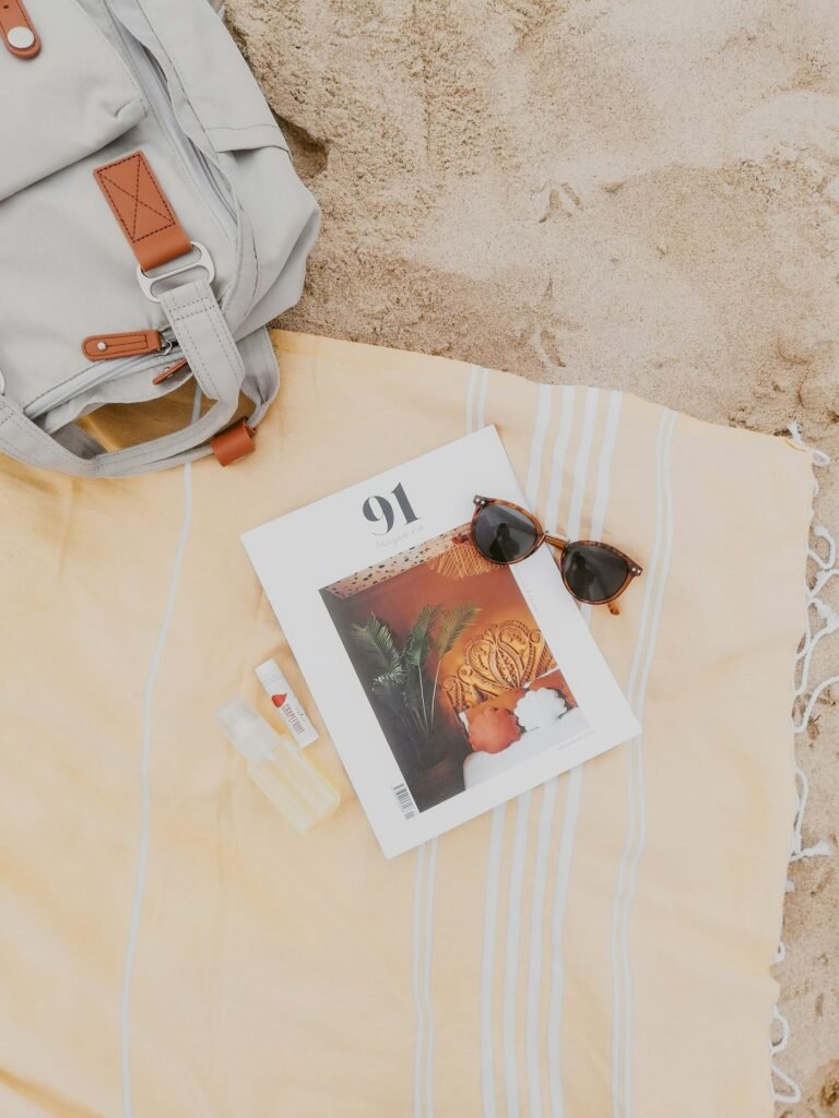 Canvas backpack, magazine and sunglasses on the sand
