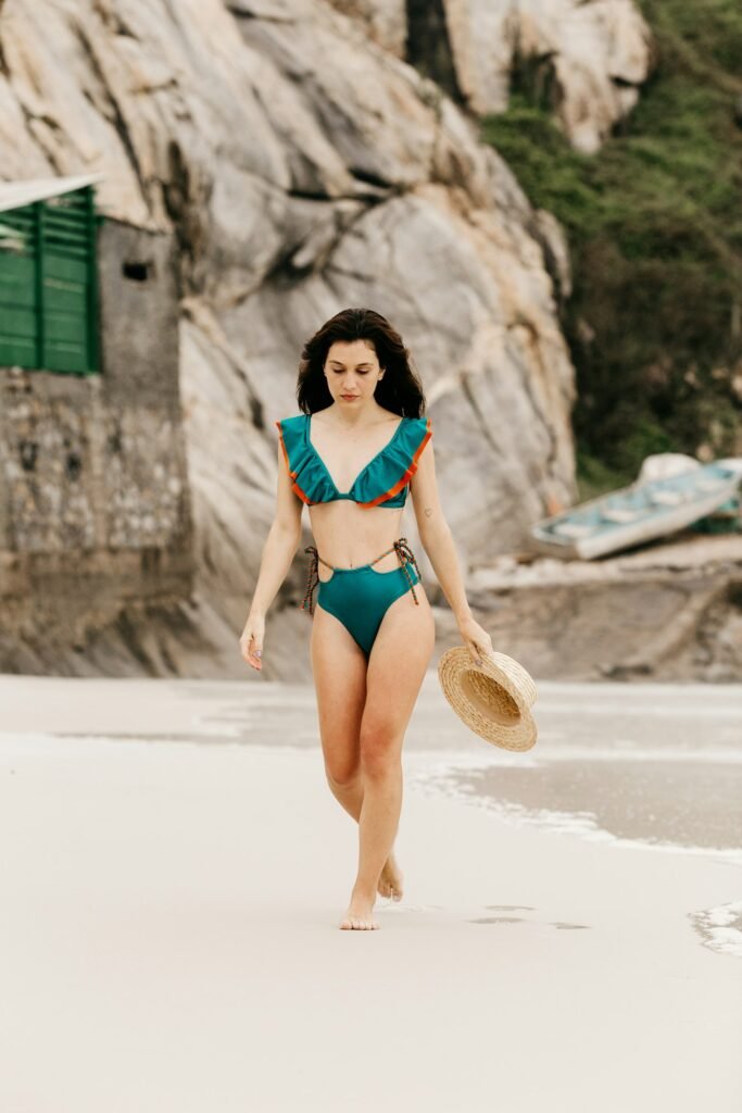 Woman in green high-waisted bikini walking on a beach
