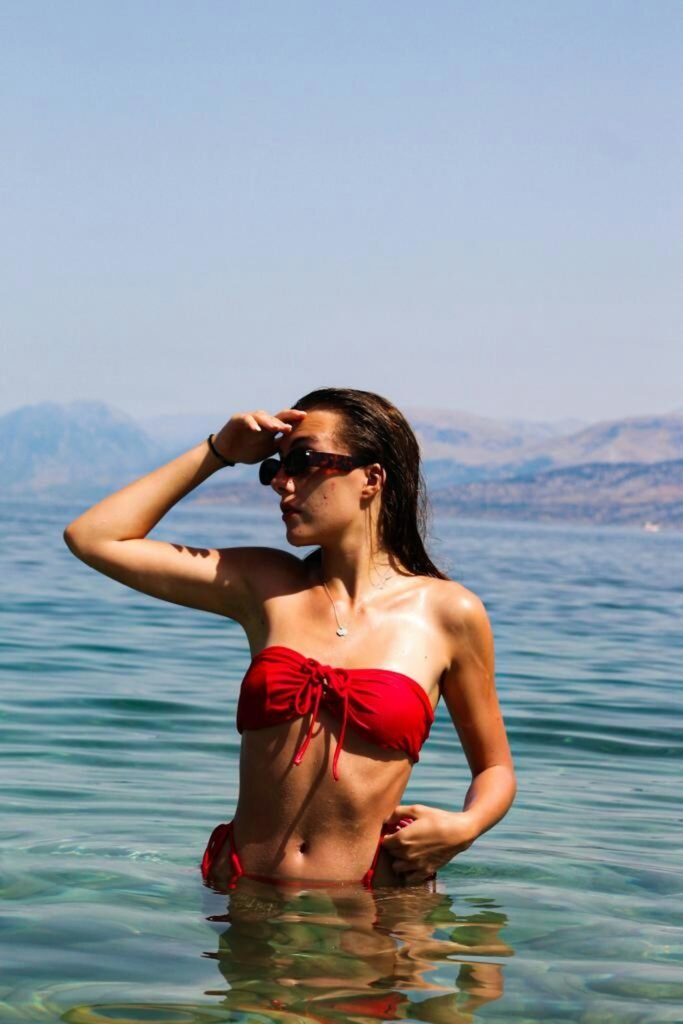 Woman in red tie-front bandeau top wading in the sea
