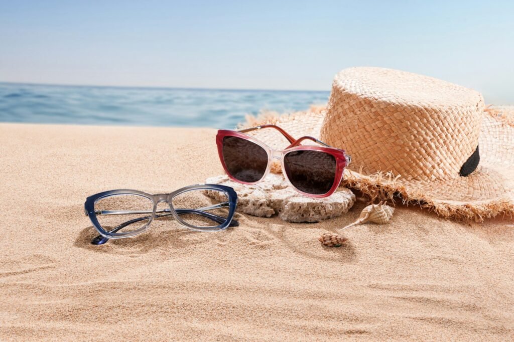 Red sunglasses and straw hat on a sandy beach