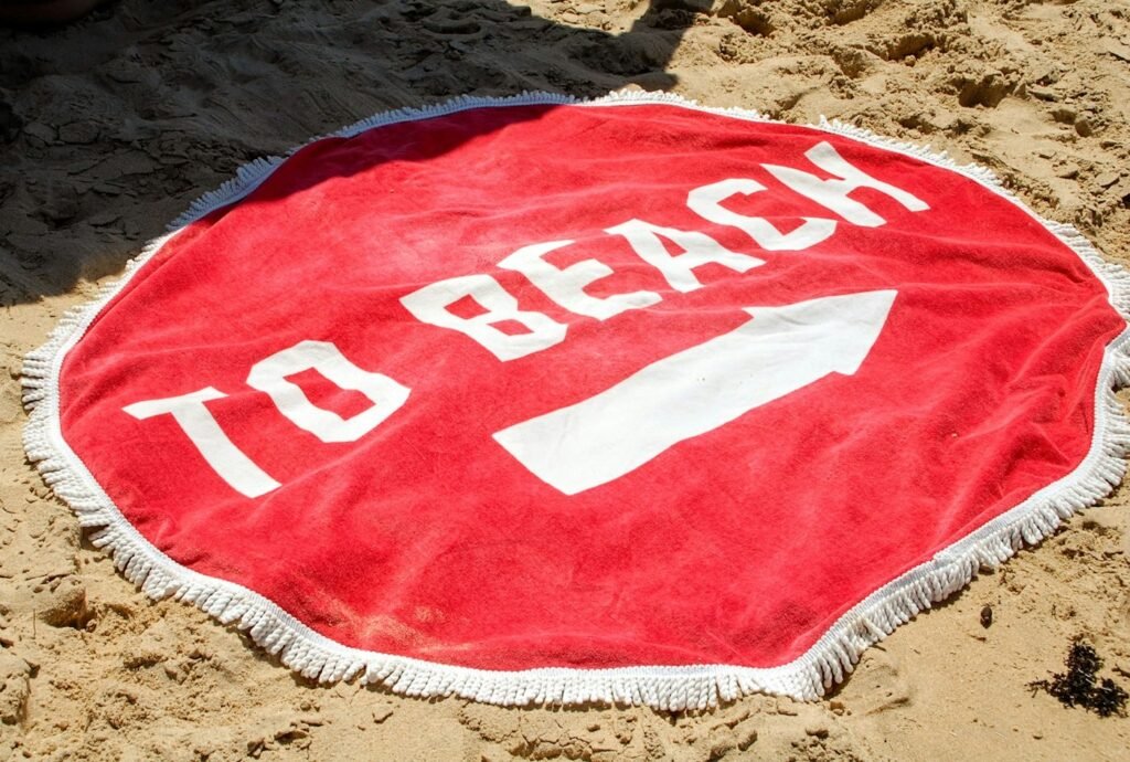 Red round fringe beach towel on sand