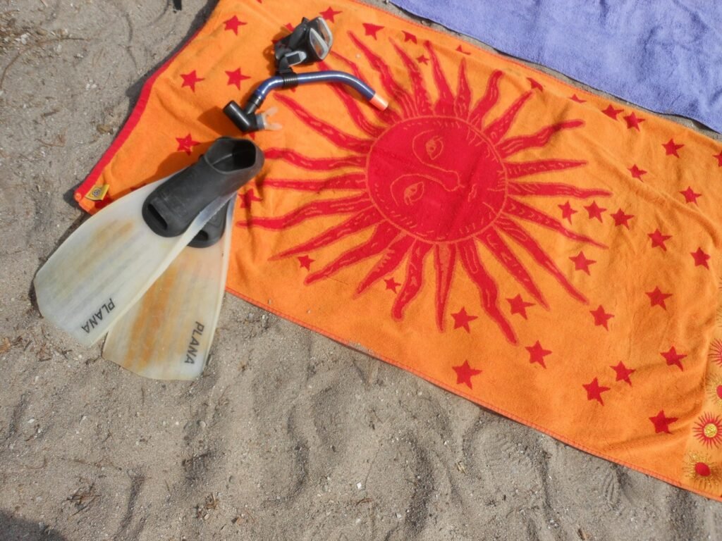Orange sun towel with snorkel fins on the beach