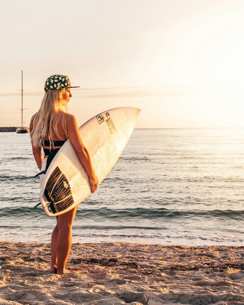 Surfer holding a board on the beach at sunset