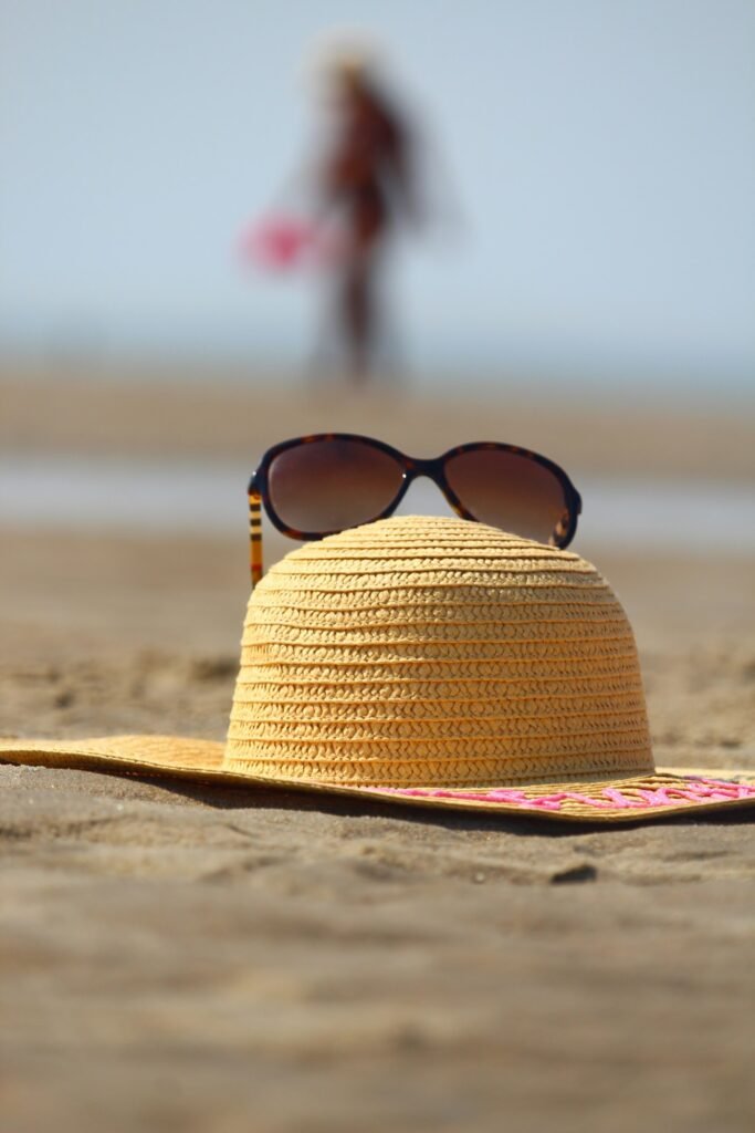 Straw sun hat and sunglasses on the sand