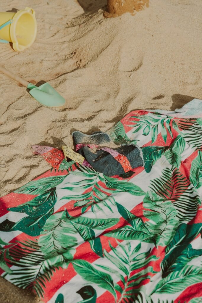 Tropical print beach towel with sunglasses on sand